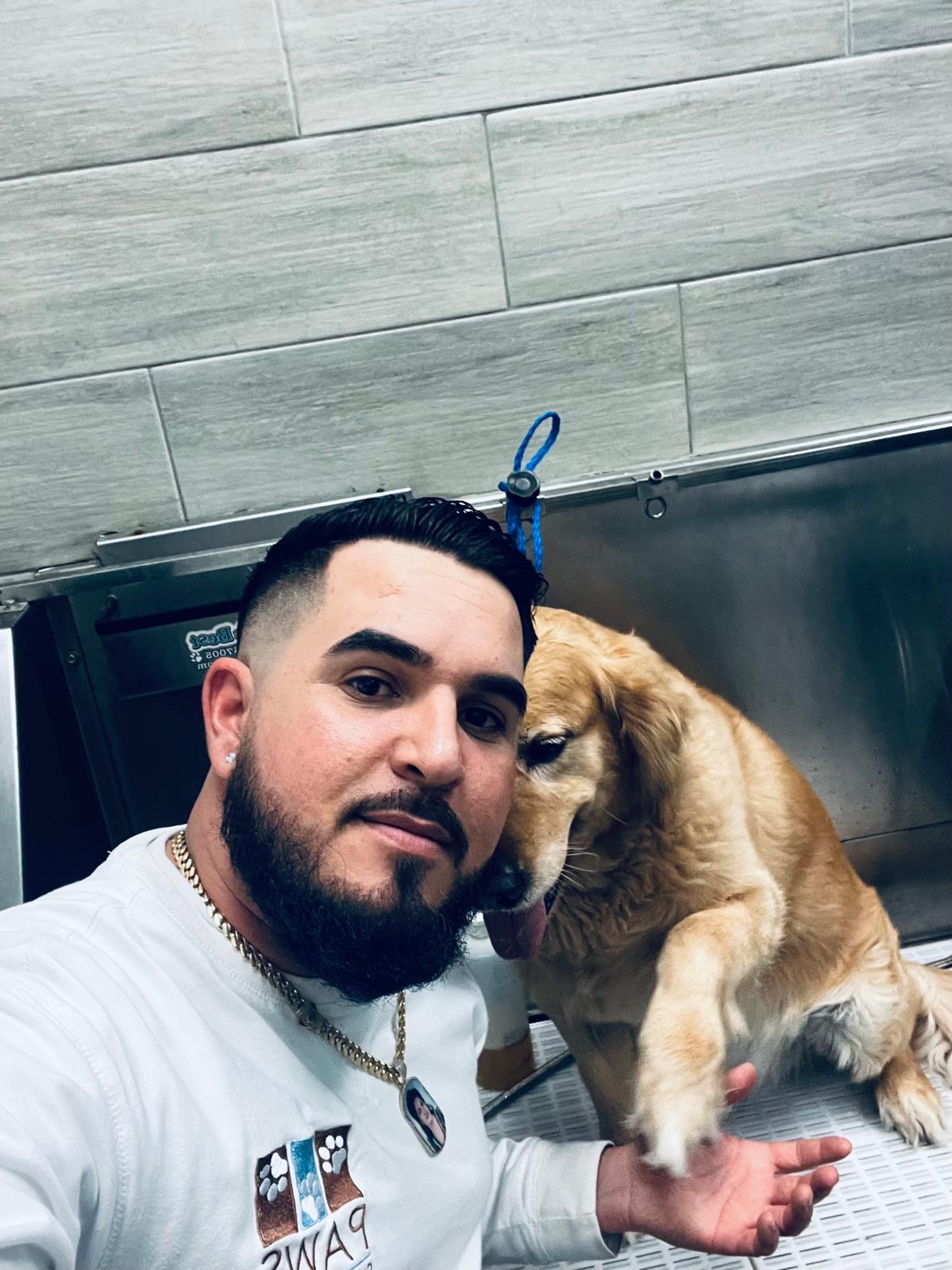 A Paws groomer with a happy golden retriever